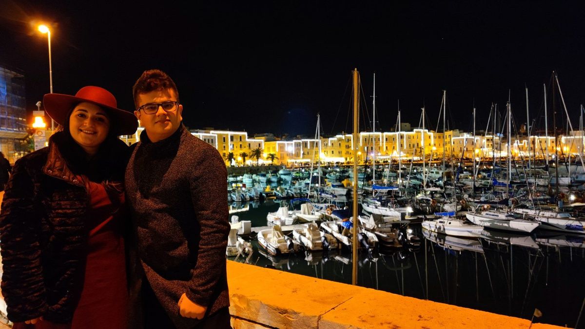 Pedro e Marialuisa di sera, davanti a un porto illuminato